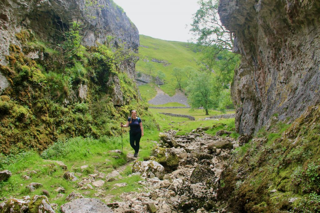 A woman walking through a gorge, with cliffs on either side. Practicing navigation during one of our workshops.