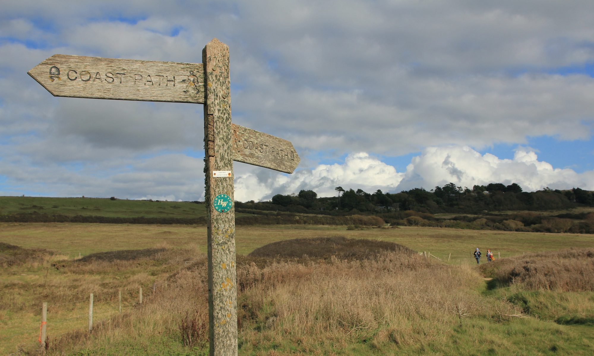 a fingerpost in the foreground showing the coastal path